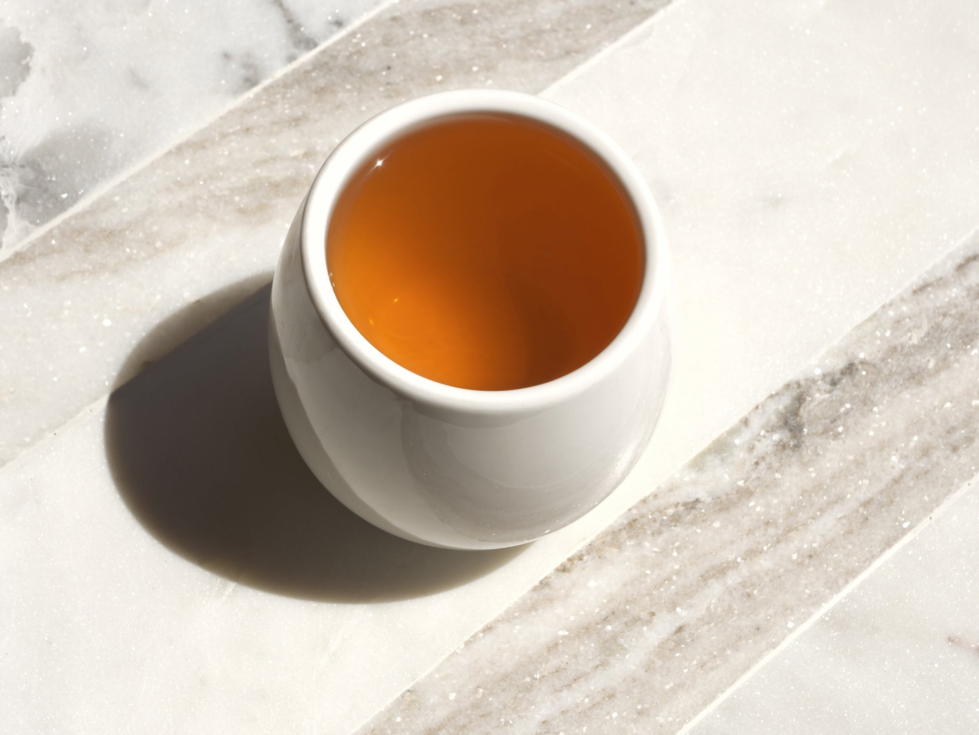 White ceramic cup filled with tea on a marble surface