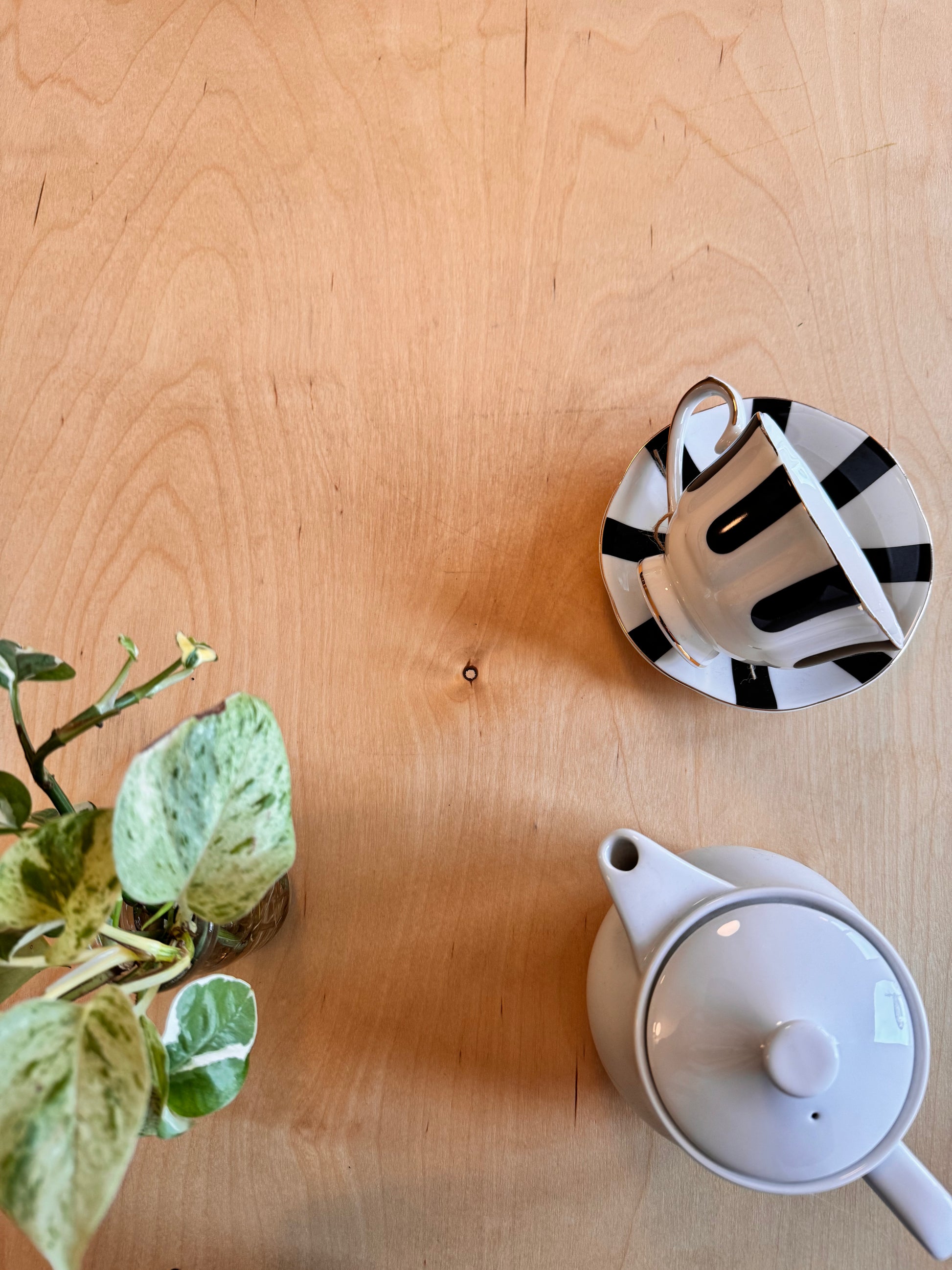 Tea set with a teapot and striped saucer on a wooden surface