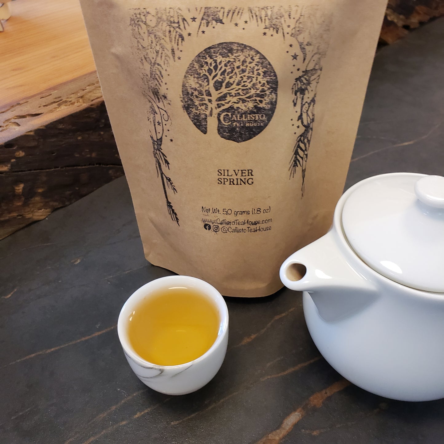 Tea packaging with a teapot and cup of tea on a wooden surface