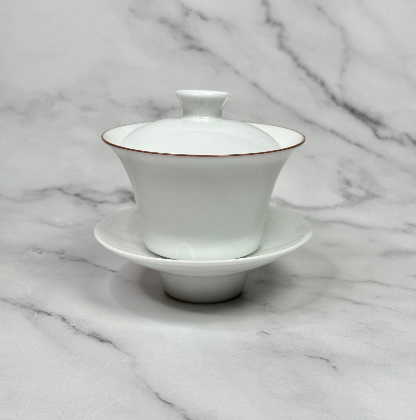 White porcelain gaiwan wih a red rim around the bowl.