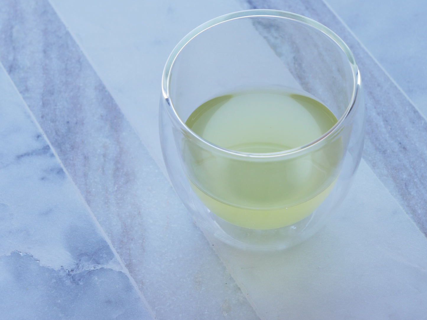 Clear glass with green tea on a marble surface