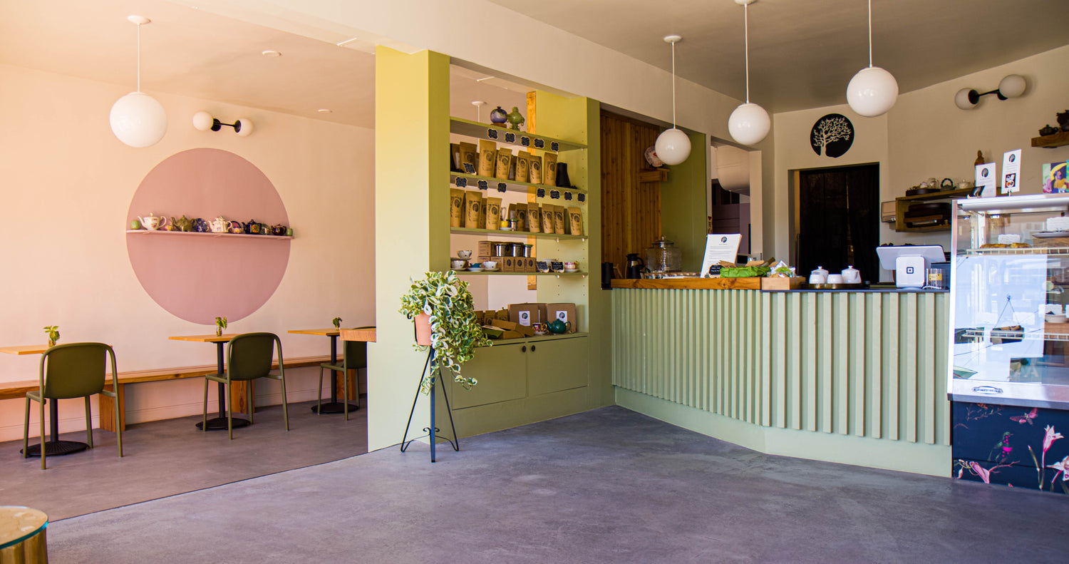 Modern cafe interior with green walls, tables, and chairs.