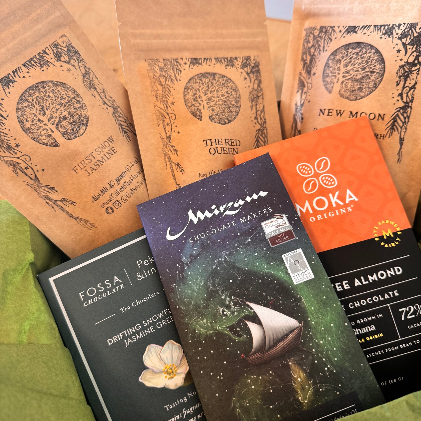 Collection of chocolate packaging and trea packages on a green surface