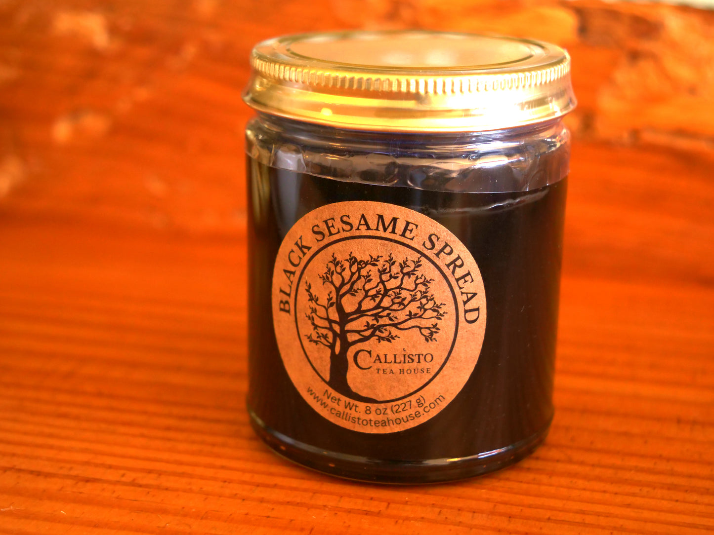 Jar of Black Sesame Spread with a gold lid on an orange background