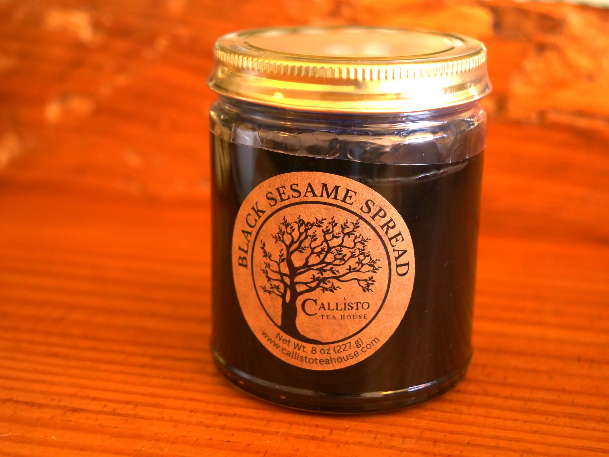 Jar of Black Sesame Spread with a gold lid on an orange background