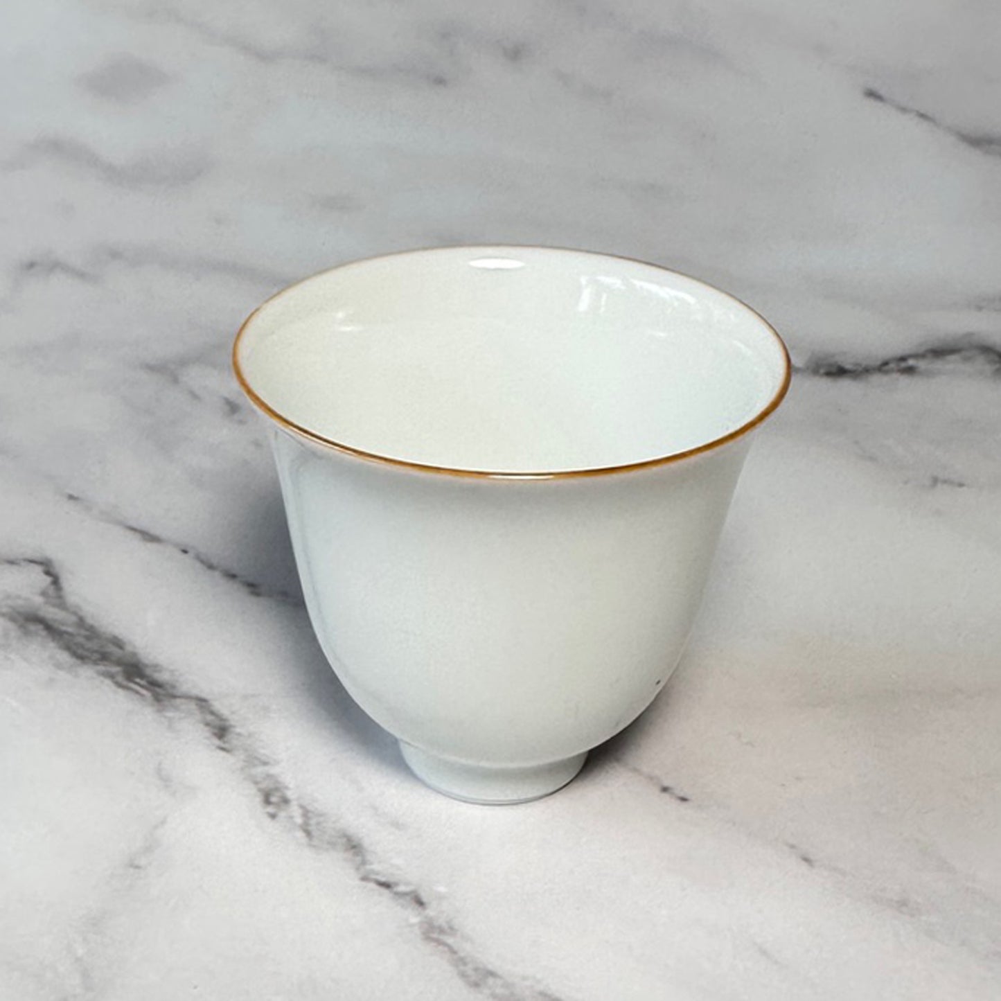Small white teacup with red rim