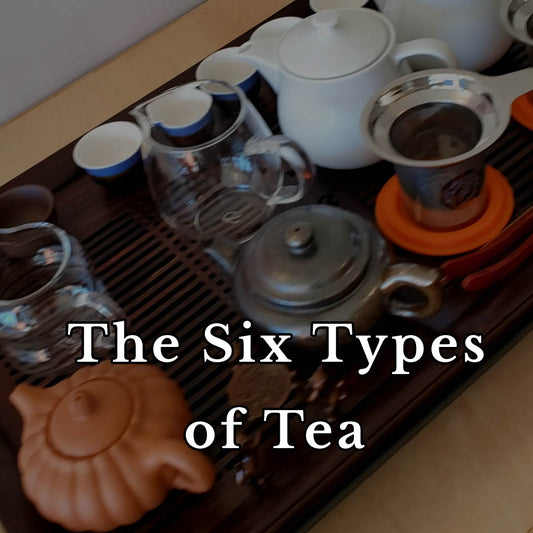Tea-making setup with teapots and cups on a wooden tray, text overlay 'The Six Types of Tea'.