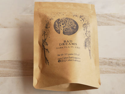 Kraft paper tea bag with 'Bad Dreams' dark tea label on a wooden surface