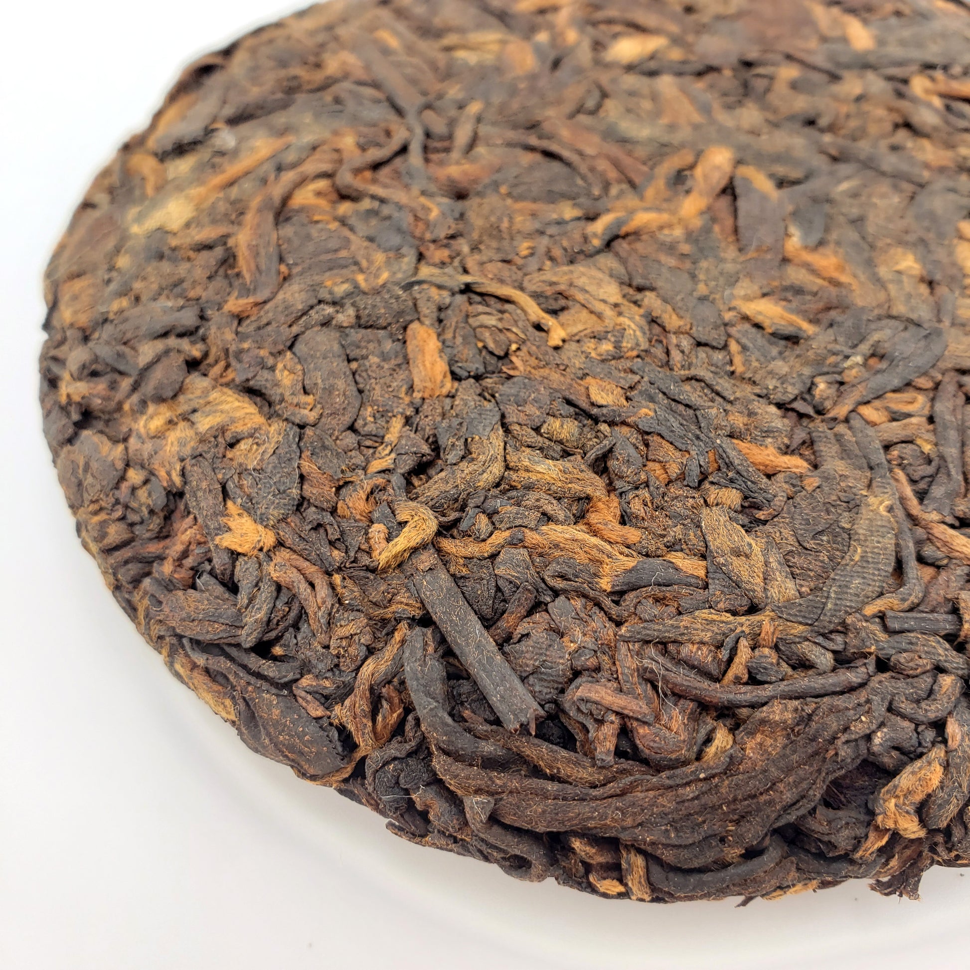 Close-up of a compressed tea cake with intricate texture on a white background