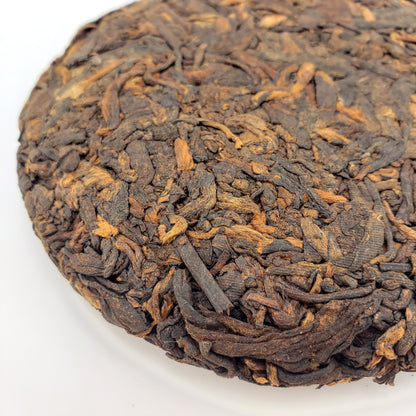 Close-up of a compressed tea cake with intricate texture on a white background