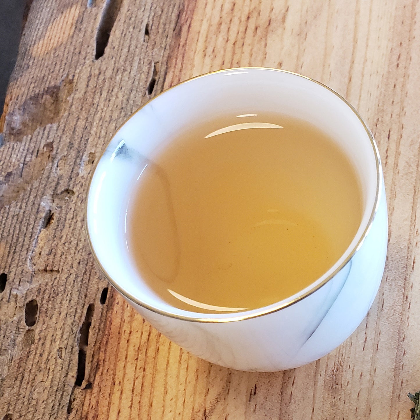 White ceramic teacup filled with tea on a wooden surface
