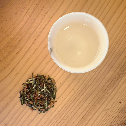 tea cup with green tea and tea leaves on a wooden surface