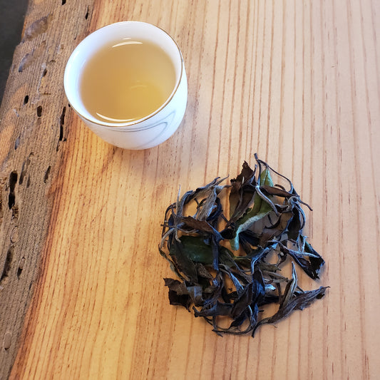 Tea leaves and a cup of tea on a wooden surface