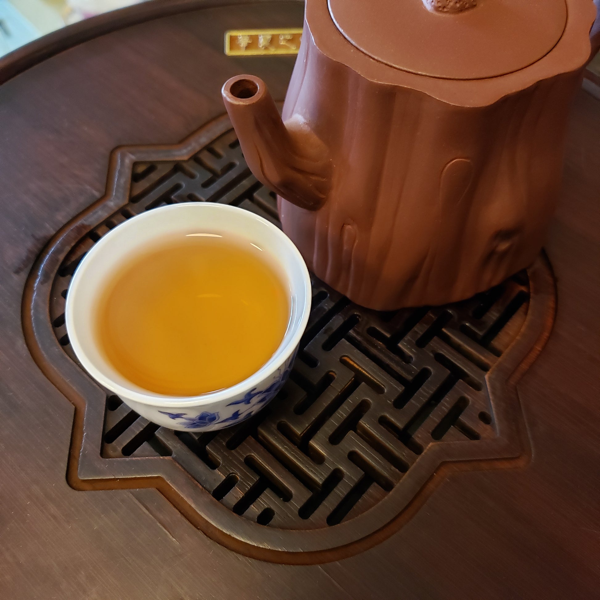 Tea pot and cup on a wooden tea tray with a woven design