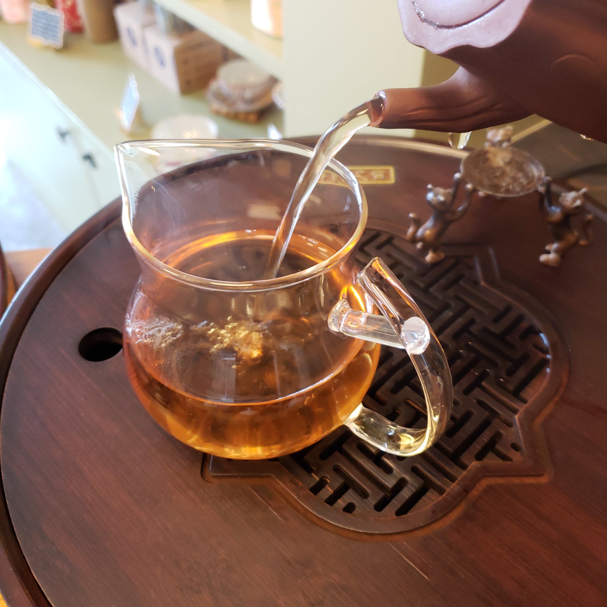 Clear glass teapot with amber liquid on a wooden surface