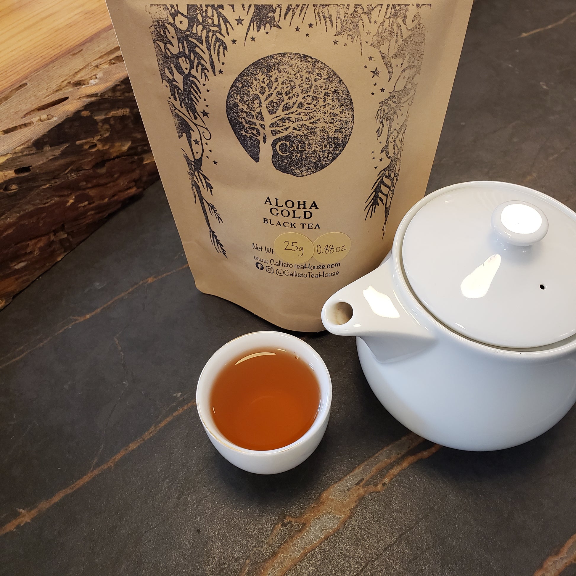Tea packaging, teapot, and cup of tea on a wooden surface