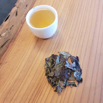 Tea leaves and a cup of tea on a wooden surface