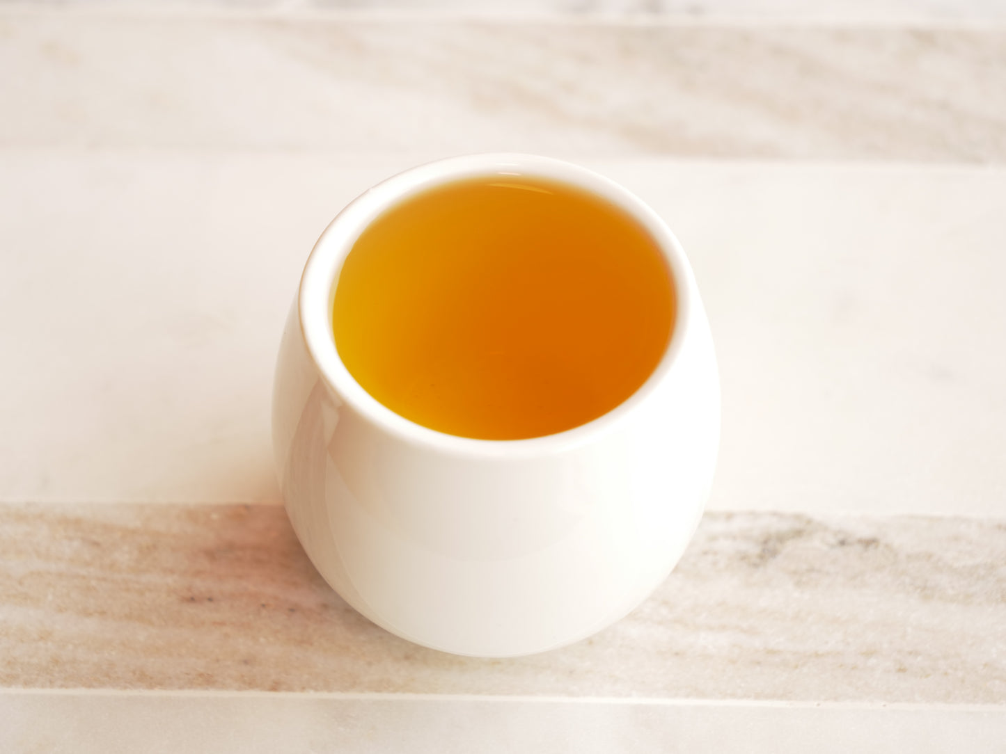 White ceramic cup filled with tea on a light marble surface