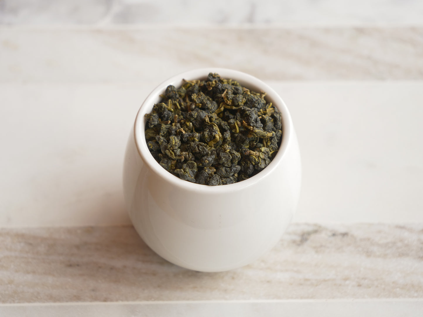 White cup filled with tea leaves on a marble surface