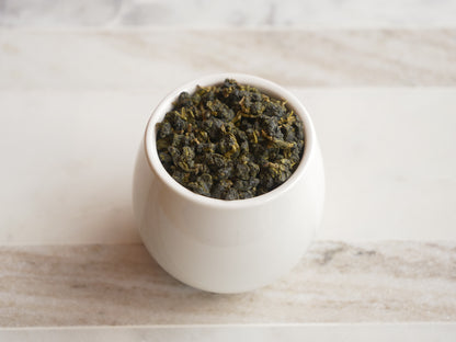 White cup filled with tea leaves on a marble surface