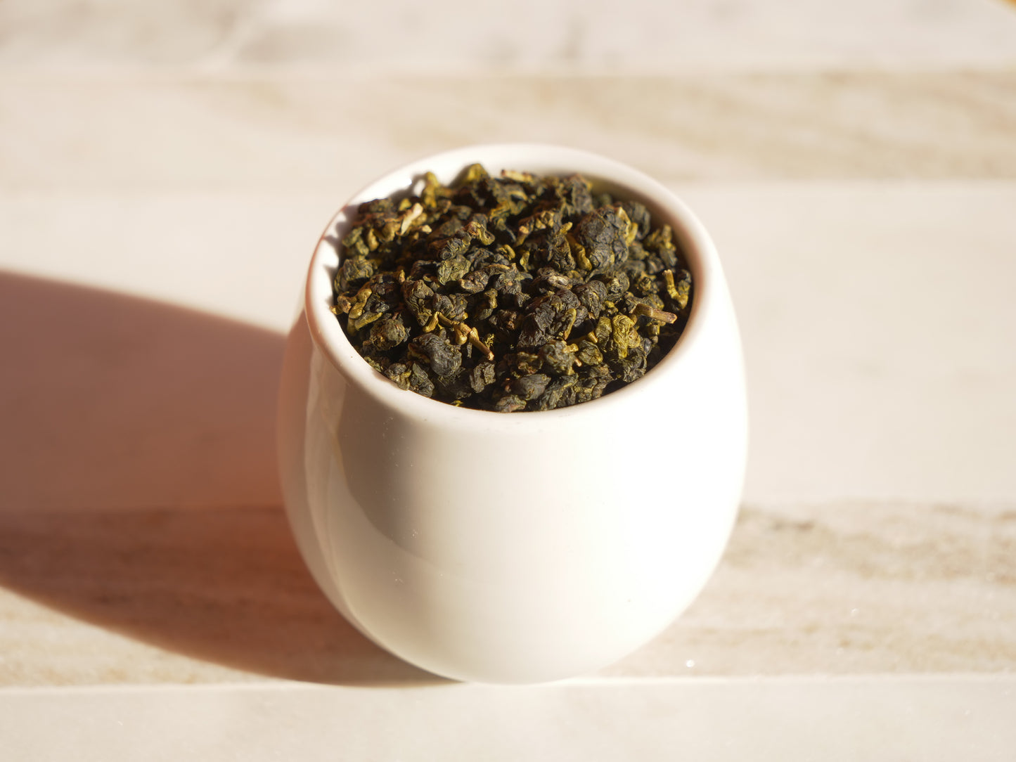 White ceramic cup filled with tea leaves on a wooden surface