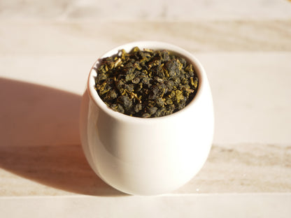 White ceramic cup filled with tea leaves on a wooden surface