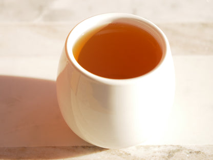White ceramic cup filled with a brewed green tea on a light background
