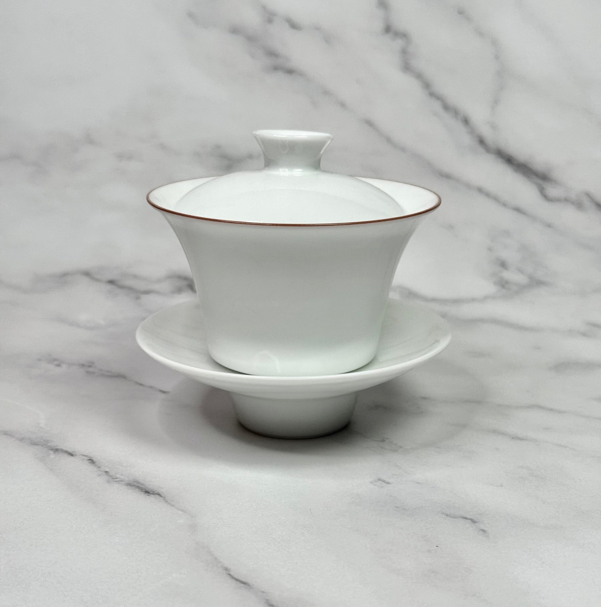 White porcelain gaiwan wih a red rim around the bowl.