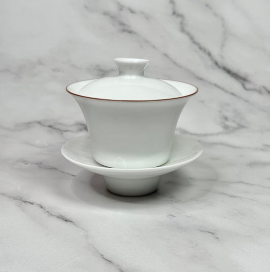 White porcelain gaiwan wih a red rim around the bowl.