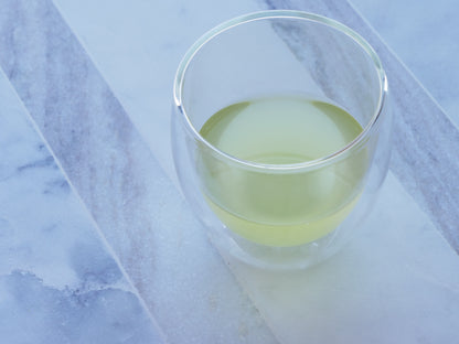 Clear glass with green tea on a marble surface