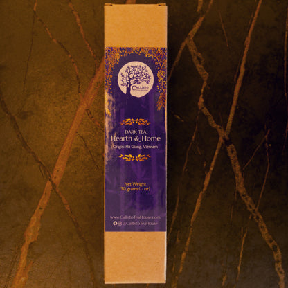 Tea packaging with a purple label and brown cardboard backing on a dark background