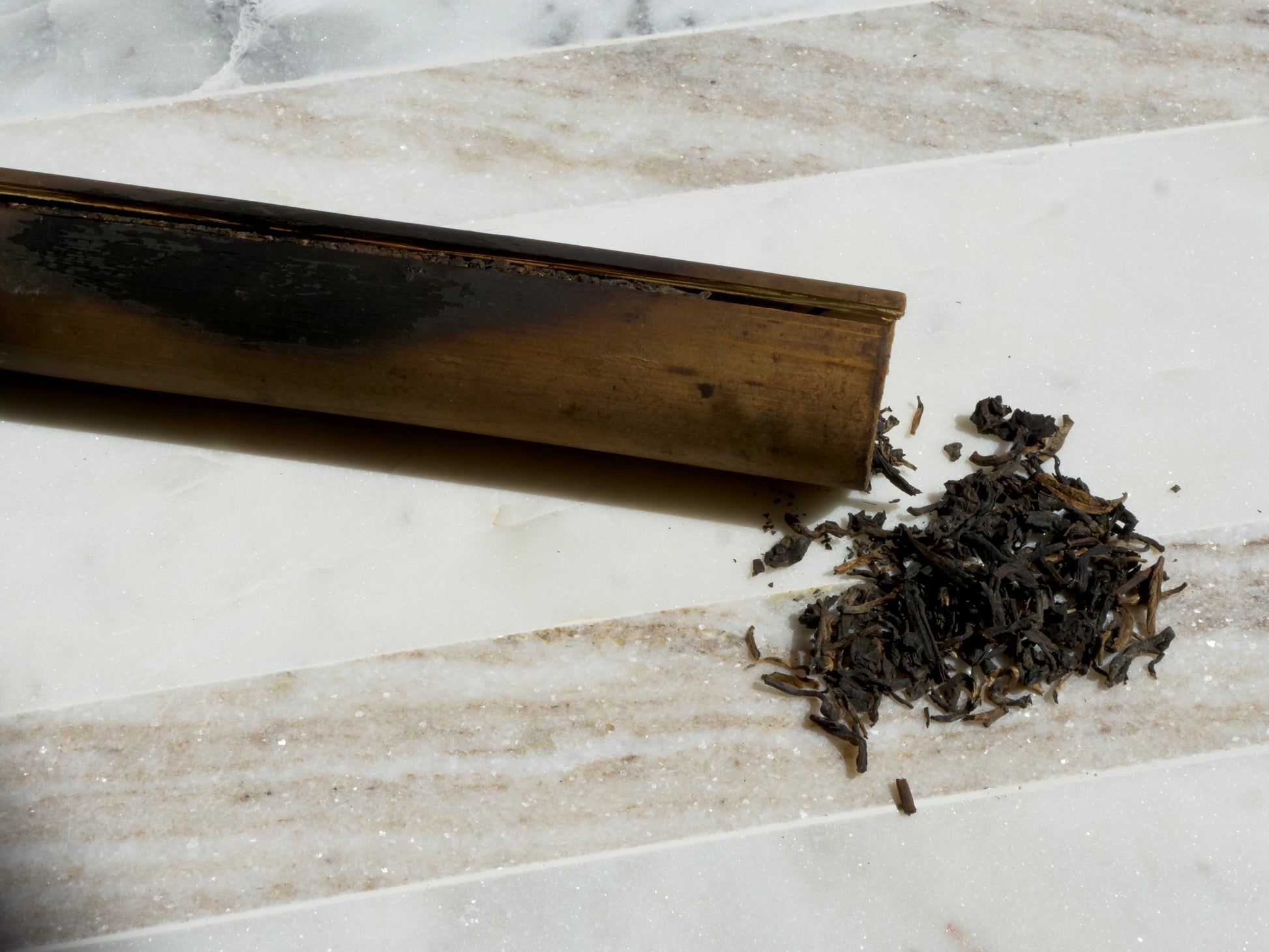 bamboo tube with tea leaves on a marble surface