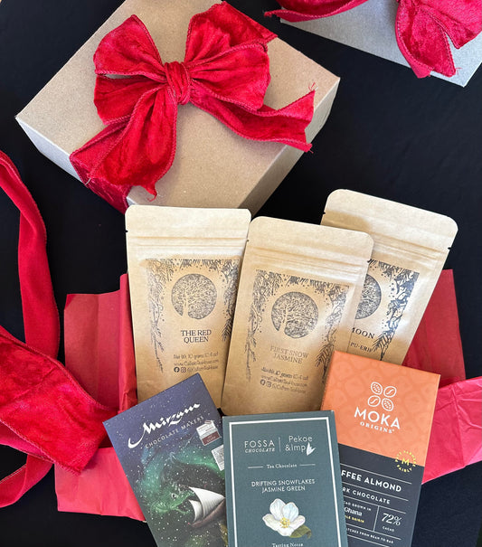 Gift set with coffee packages, a red bow, and a card on a dark surface